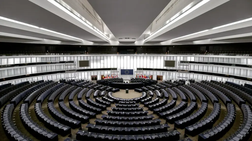 Tuščia moderni parlamentinė posėdžių salė, simbolizuojanti svarbius politinius sprendimus ir valstybės biudžetą.
