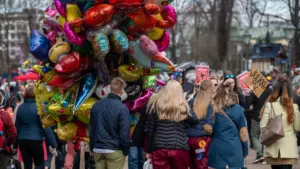 Spalvoti balionai miestelio šventėje, kurioje susirinkę žmonės džiaugsmingai leidžia laiką lauke parke.