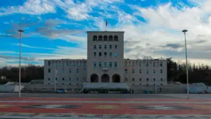 Didelis pilkas pastatas po ryškiai mėlynu dangumi atidarymo šventės proga.