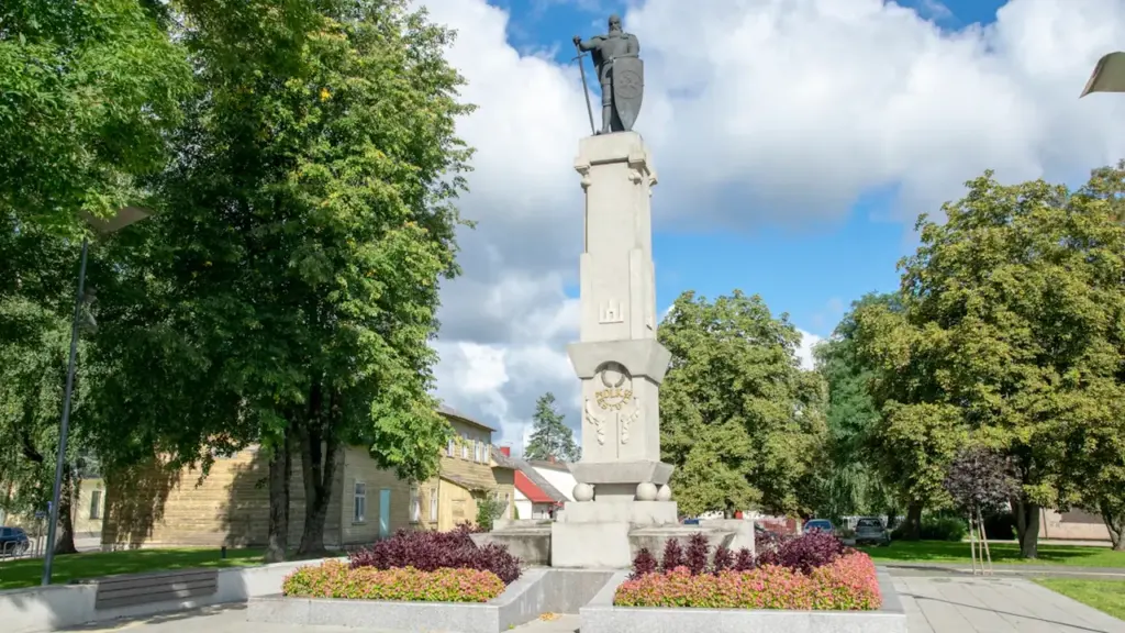 Istorinis paminklas su vyro statula, įamžinantis Lietuvos praeitį ir kultūrinį palikimą.