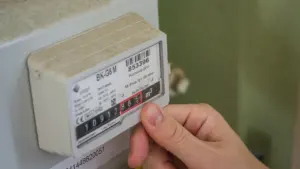 Vyriškos rankos tikrina elektros skaitiklio rodmenis namų sąlygomis kasdienei kontrolei.