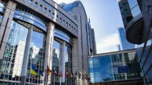 Moderni Europos Parlamento pastato architektūra su vėliavomis Briuselyje, Belgijoje, saulėtą dieną.