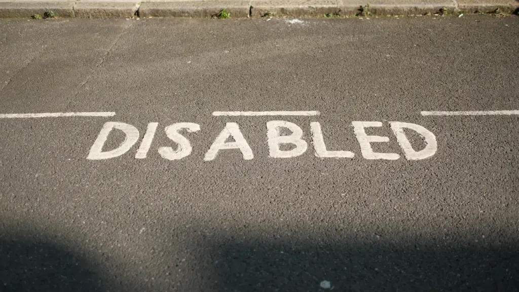 Ant asfaltinės dangos dažais nupieštas užrašas „Disabled“, žymintis stovėjimo vietą neįgaliesiems.