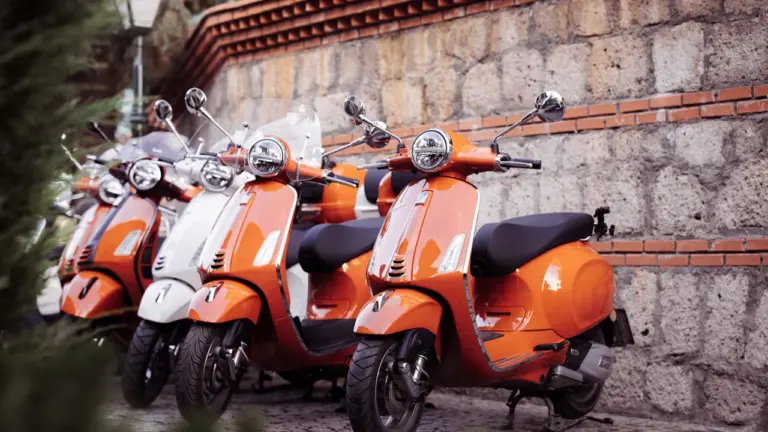 Ryškūs motoroleriai pastatyti ant akmenimis grįstos gatvės Europos judumo savaitės kontekste